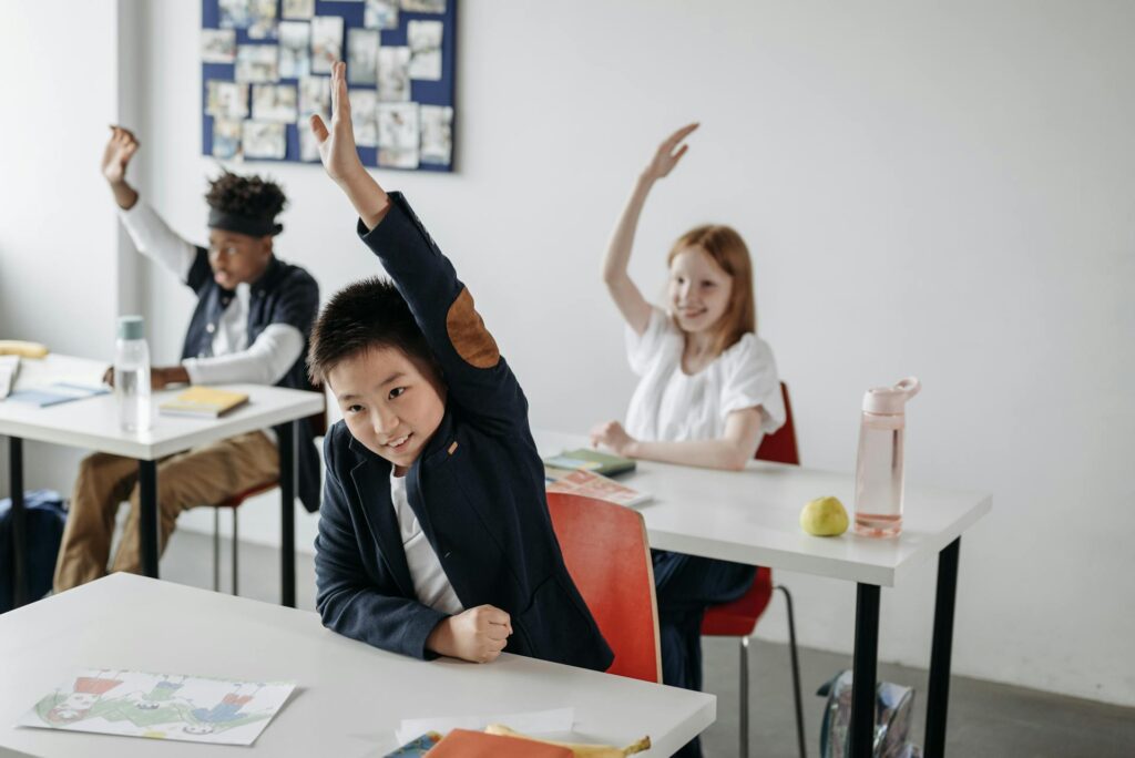 students raising hands in class