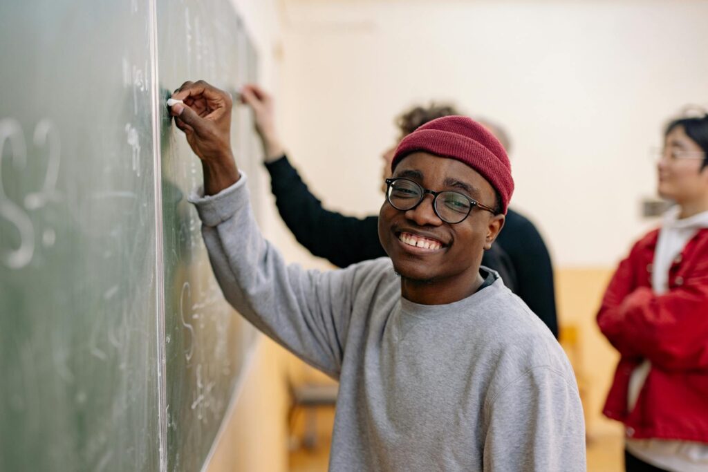 student smiling while writing on class board